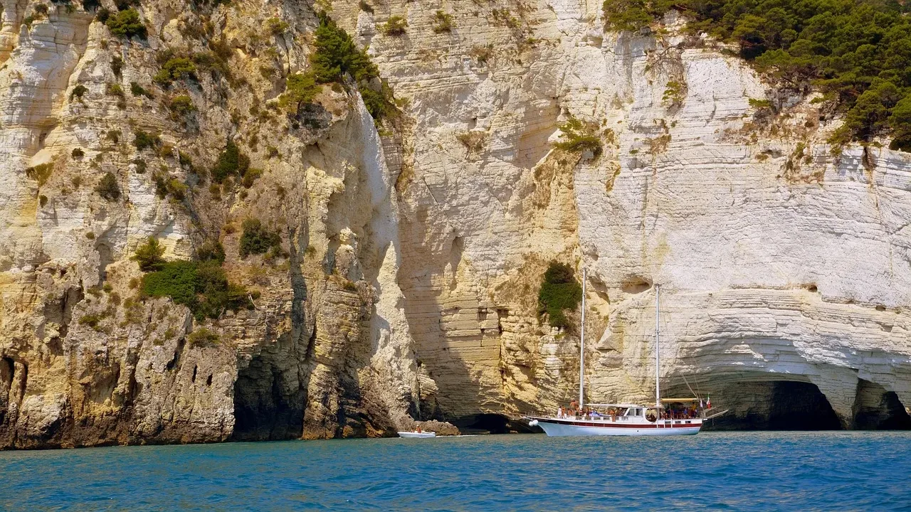 Barca da escursione sotto le falesie calcaree della costa del Gargano