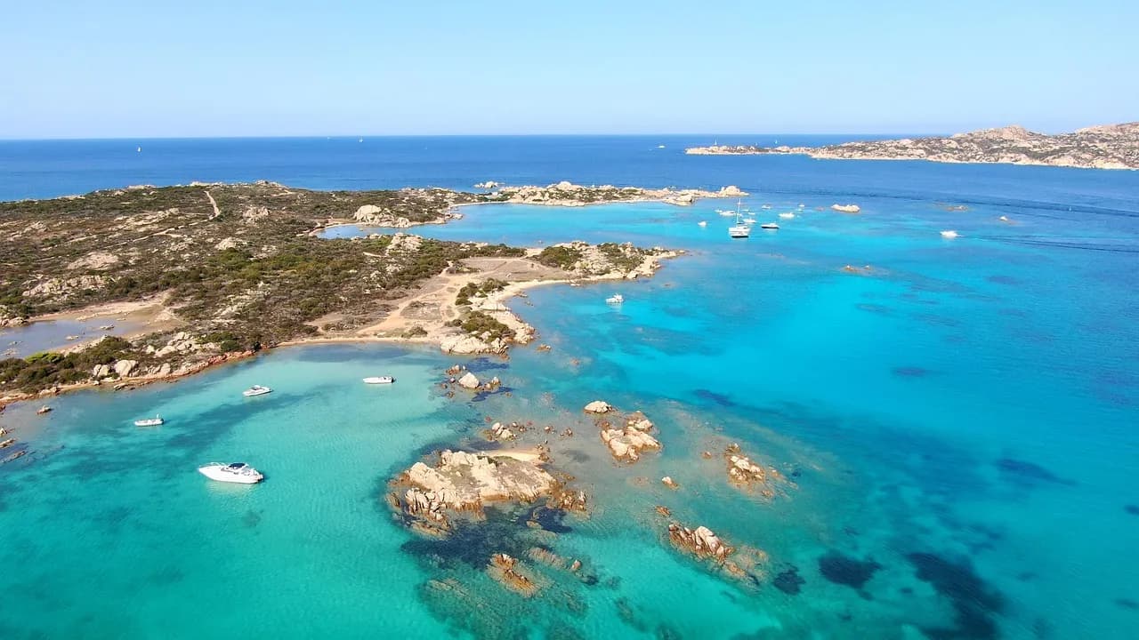 Vista aerea dell'arcipelago di La Maddalena con acque turchesi, isolotti di granito e barche in navigazione