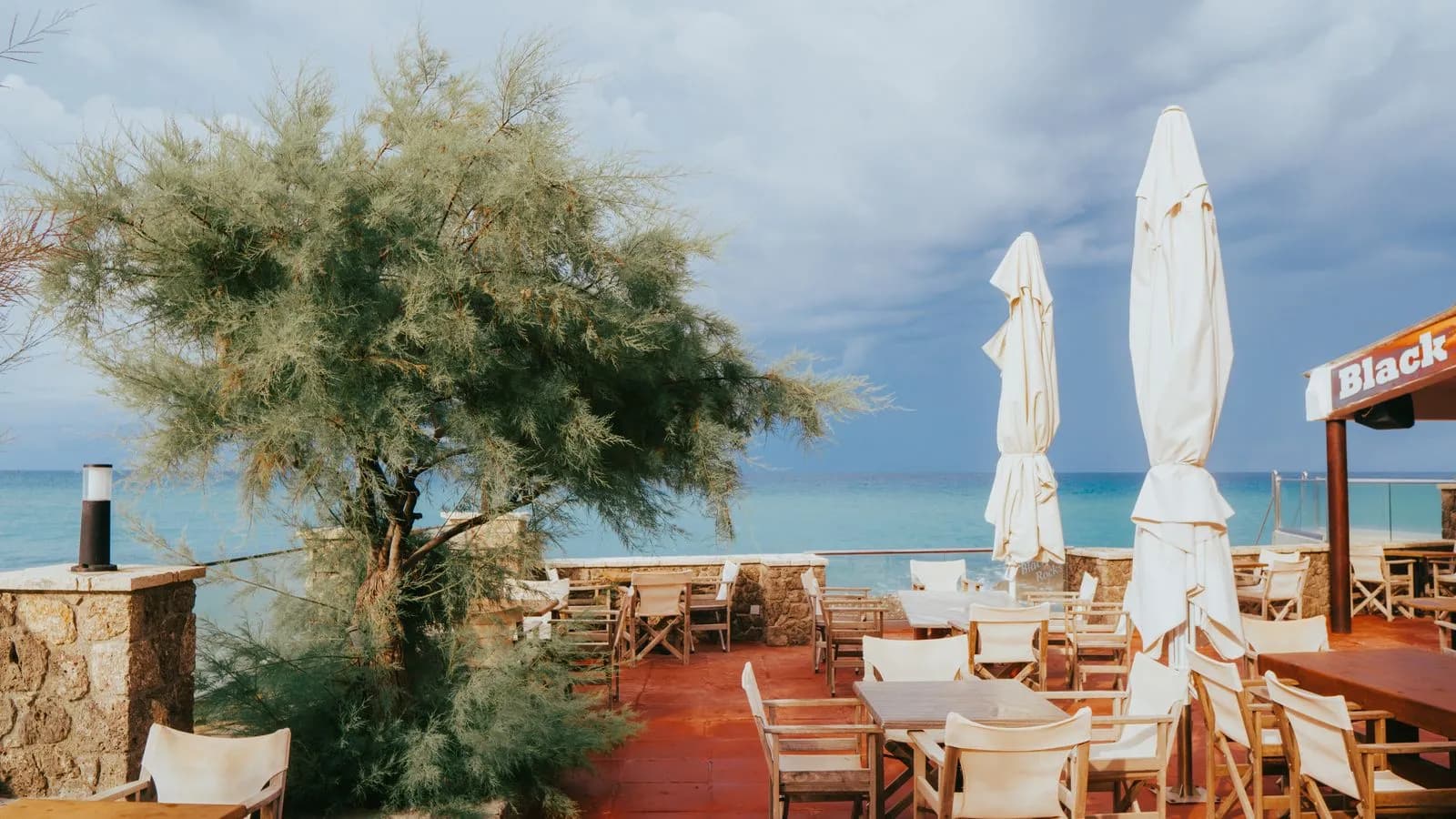 Terrazza di un ristorante con tavoli vuoti affacciati sul mare, pronta per il servizio