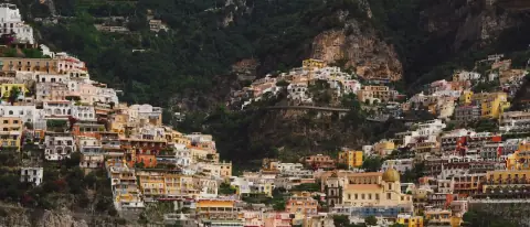 Barca sul mare davanti a un borgo a strapiombo della Costiera Amalfitana