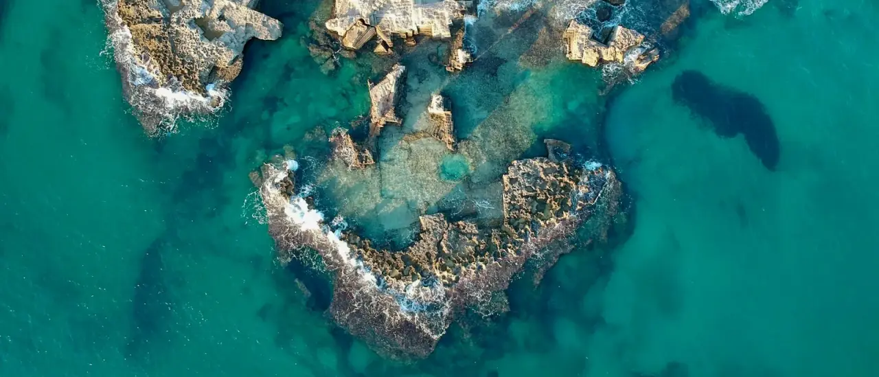 Isolotto roccioso con acque turchesi lungo la costa italiana, vista aerea dal mare
