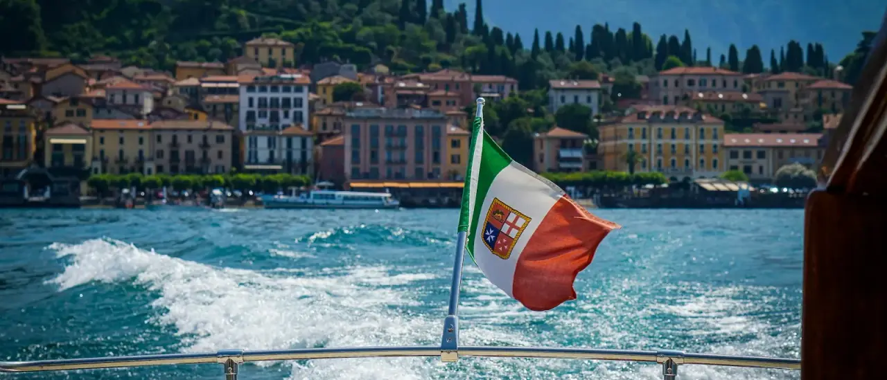 Vista di Bellagio dal pozzetto di una barca con la bandiera italiana, Lago di Como