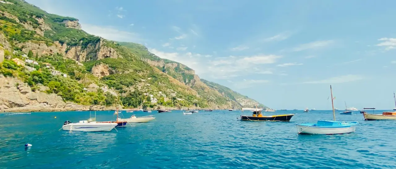 Piccole barche a motore ancorate lungo la costa della Campania, viste dal mare