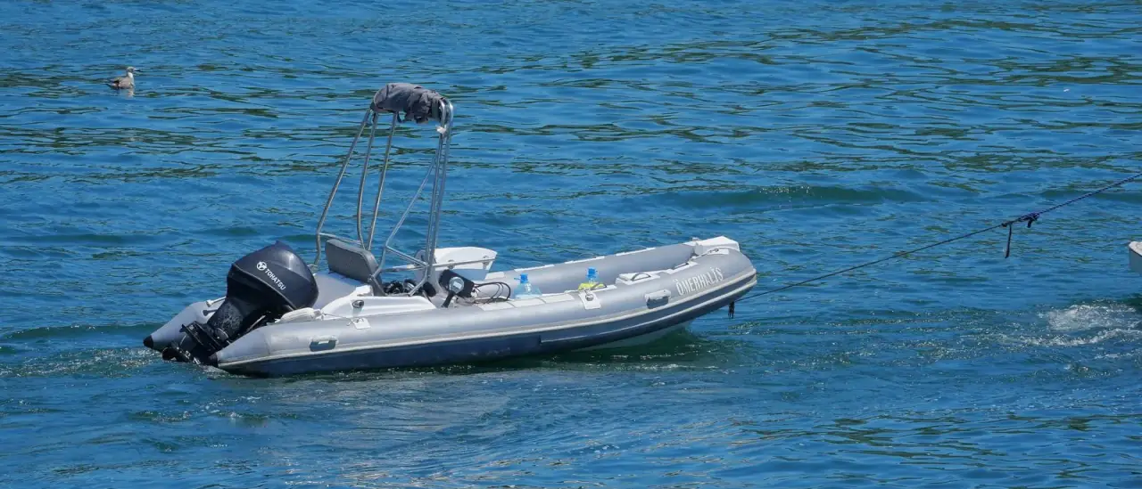 Gommone con motore fuoribordo ormeggiato in mare aperto su acqua blu