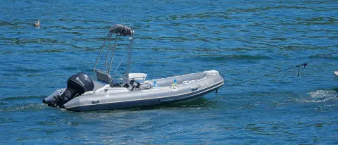 Gommone semirigido all'ancora, con tubolari e motore fuoribordo in evidenza
