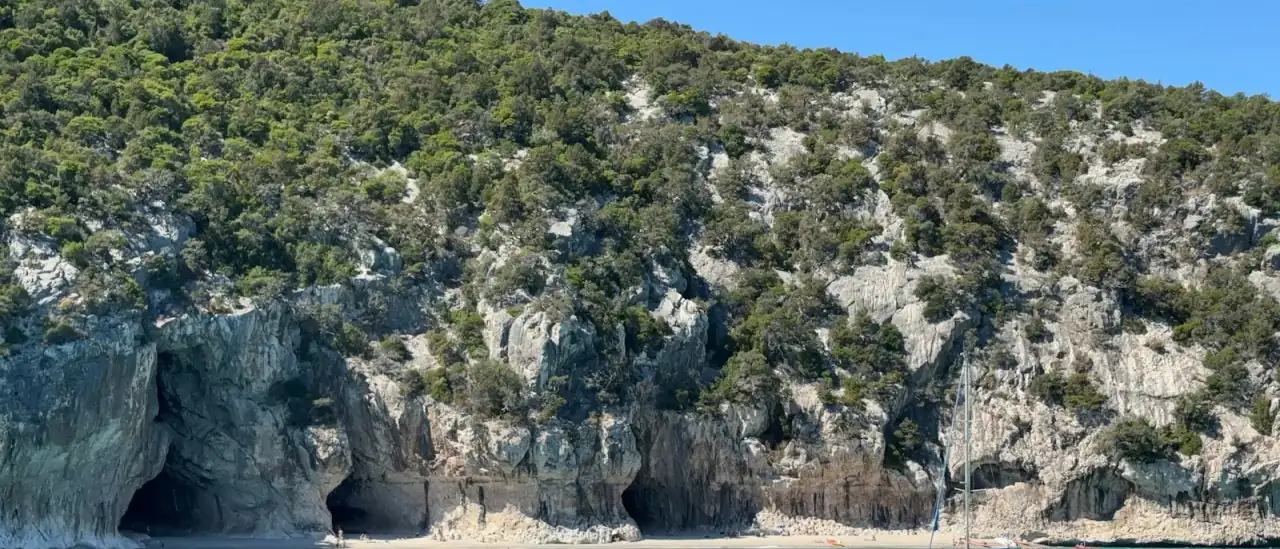 Gommoni e piccole barche all'ancora in una baia dall'acqua turchese lungo una costa rocciosa