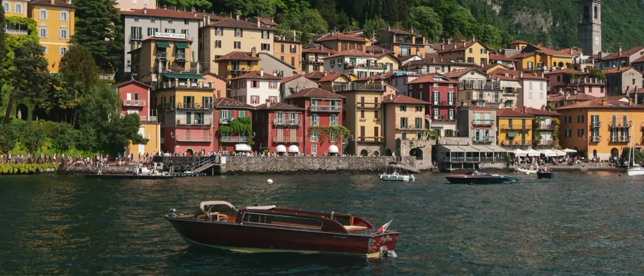Barca in legno sul Lago di Como davanti al borgo colorato di Varenna