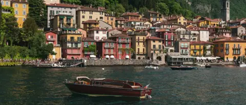 Barca in legno sul Lago di Como davanti al borgo colorato di Varenna