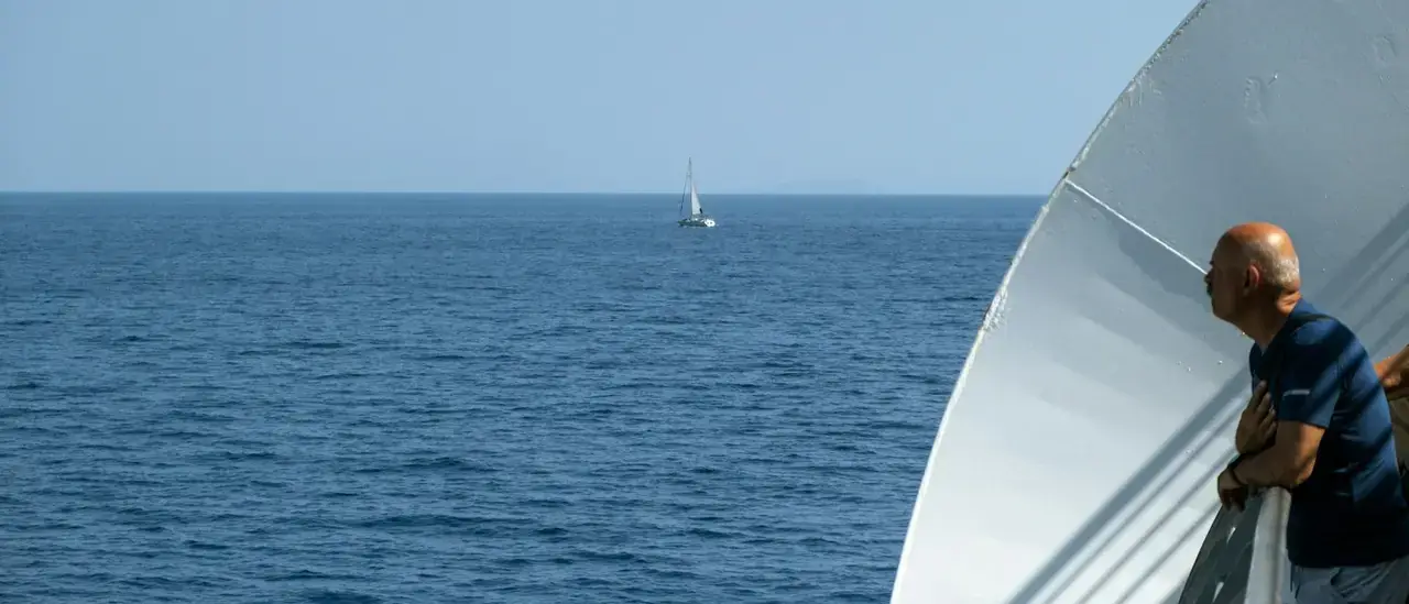 Passeggero guarda l'orizzonte dal parapetto di una nave nel mare calmo