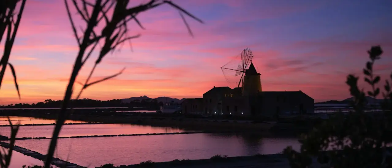 Un mulino a vento delle saline dello Stagnone di Marsala stagliato contro il cielo al tramonto