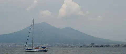 Una barca a vela naviga nel golfo di Napoli con il Vesuvio sullo sfondo