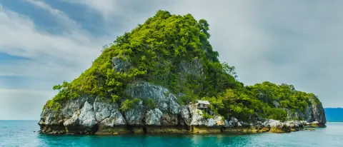 Isola rocciosa con vegetazione mediterranea e acqua turchese dell'arcipelago pontino