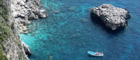 Caletta italiana con acqua turchese, scogliere e piccole barche all'ancora