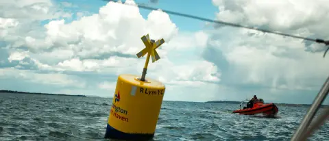Boa di segnalazione gialla in mare con una piccola barca