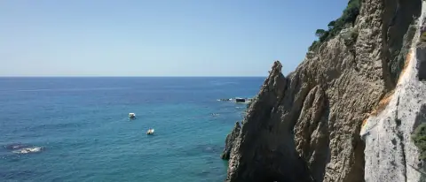 Falesia di tufo con arco naturale e piccole barche ancorate sulla costa dell'isola di Ponza