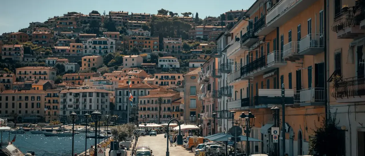 Il lungomare e le case colorate di Porto Santo Stefano, all'Argentario, con le barche ormeggiate nel porto