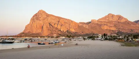 La spiaggia di San Vito Lo Capo con barche tirate a riva e il Monte Monaco sullo sfondo al tramonto