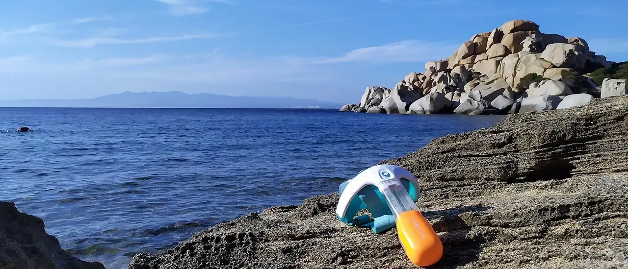 Maschera da snorkeling appoggiata su scogliera rocciosa, mare aperto sullo sfondo