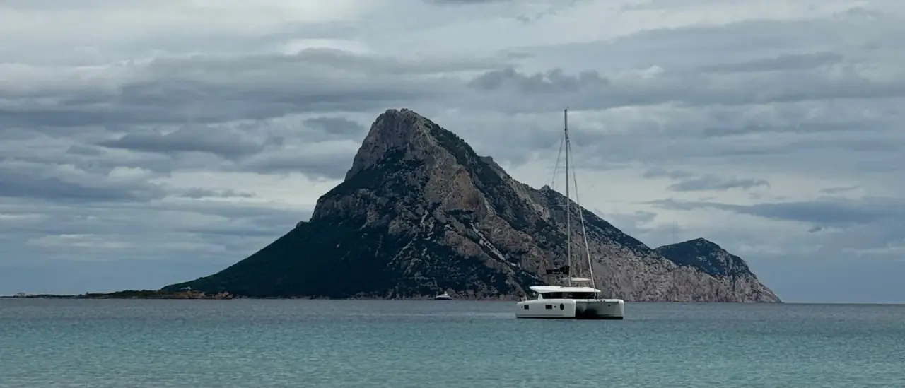 Barca a vela naviga davanti all'Isola di Tavolara, Sardegna
