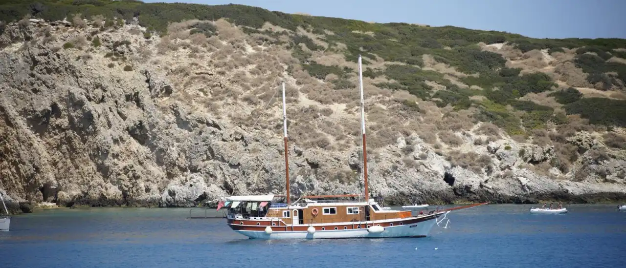 Yacht in legno all'ancora vicino alla costa rocciosa di San Nicola, Isole Tremiti