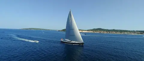 Barca a vela a vele spiegate lungo la costa in una giornata di sole